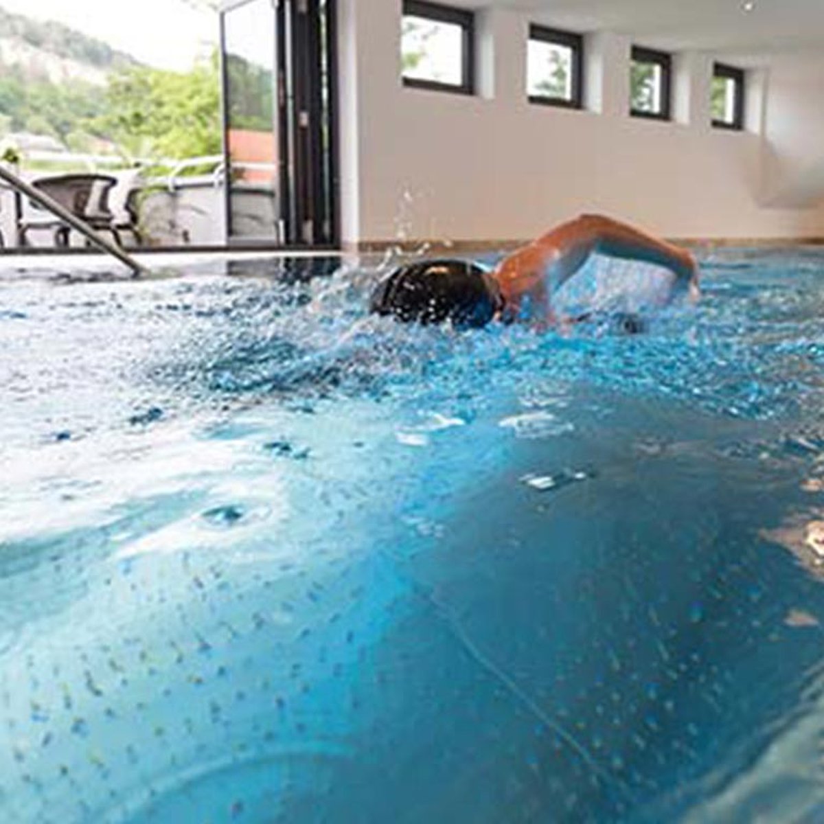 Eine Person schwimmt in einem Pool mit Gegenstromanlage.