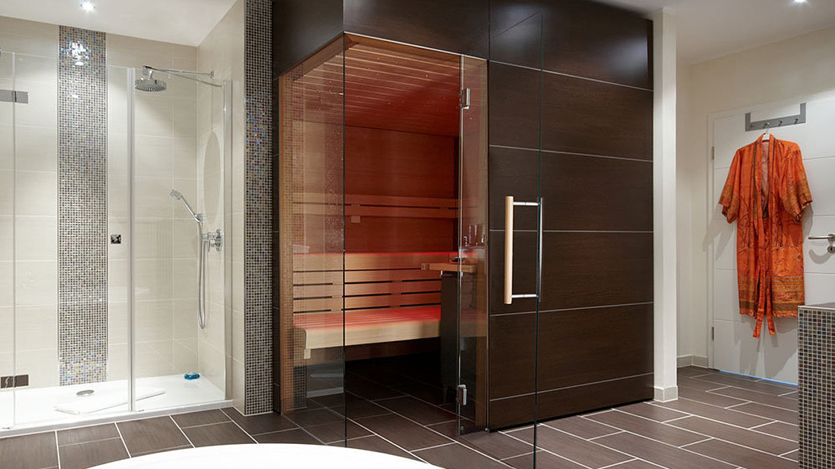 Een saunacabine met een glazen raam van vloer tot plafond. Daarnaast een doucheruimte.