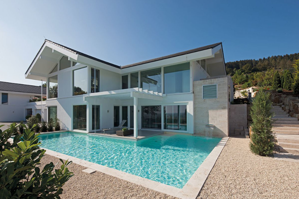 Ein weißes Wohnhaus mit einem Pool im Vordergrund.