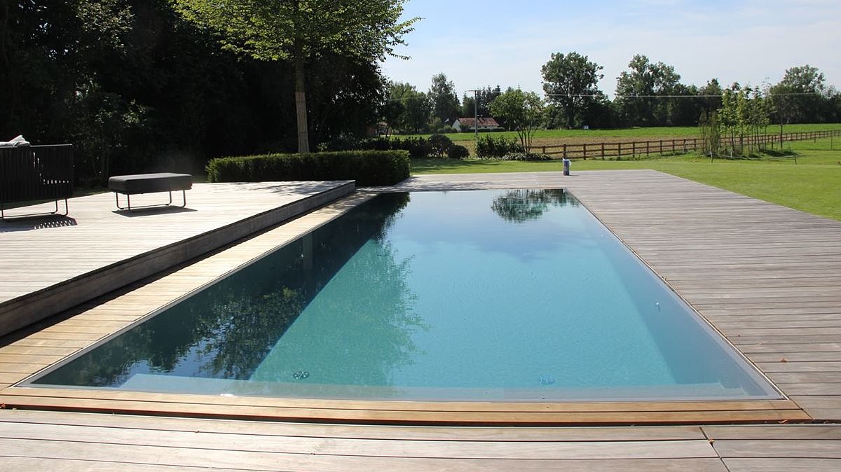 Ein Pool in einem Garten mit Holzumrandung.
