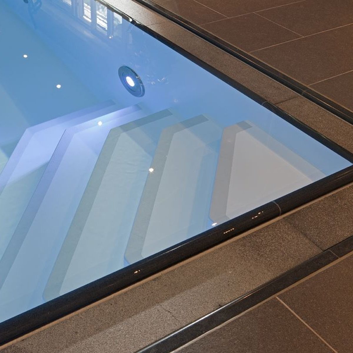 Ein Pool mit Einstiegstreppe über Eck und einem ins Becken integrierten LED-Strahlers zur Beleuchtung des Einstiegsbereichs.