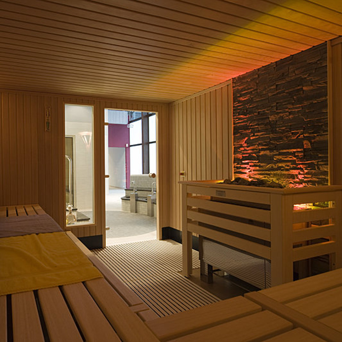 Interieur van een sauna waarvan het kachelgedeelte verlicht is.