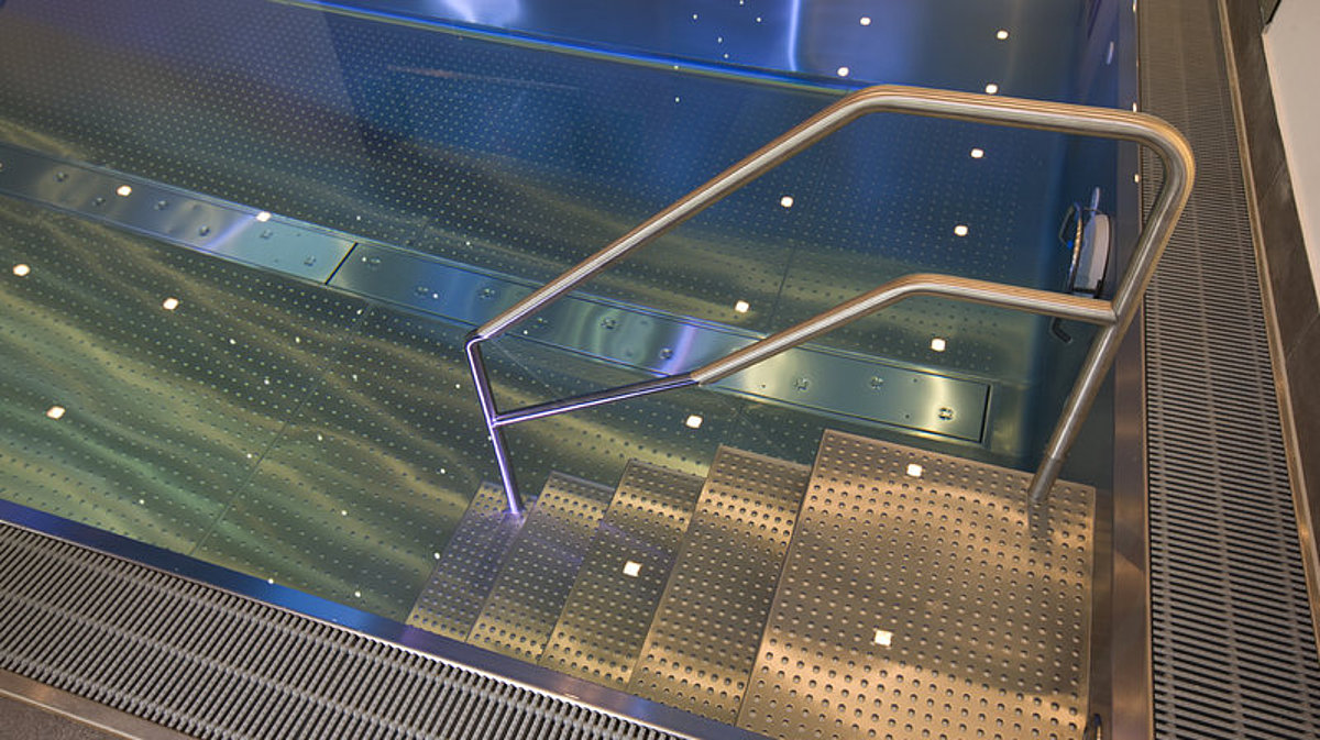 Ein Überlaufbecken aus Edelstahl. Der Fokus liegt auf der Überlaufrinne und der Treppe.
