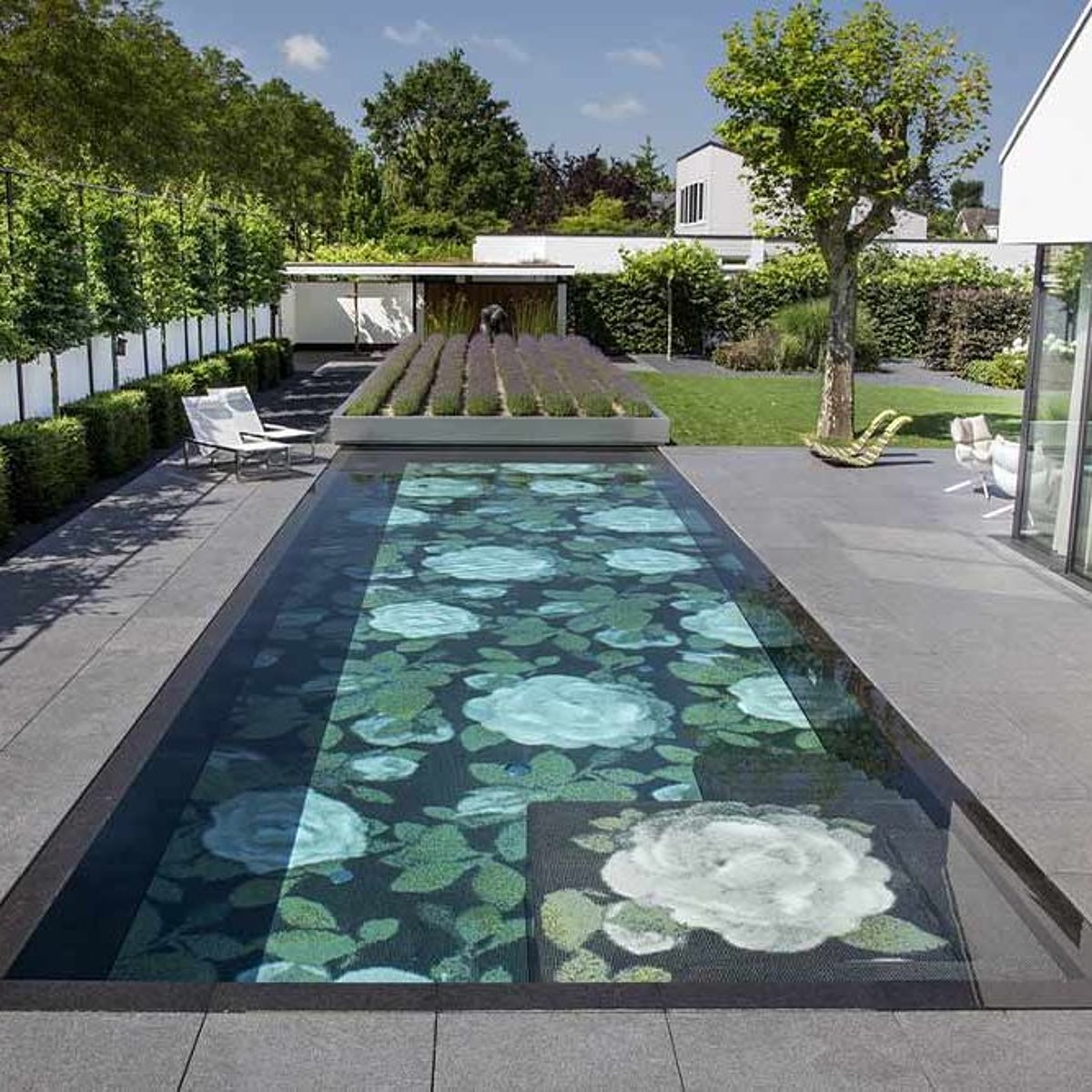 Een uitgebreid ontworpen patiozwembad met bloemenmozaïek en mobiel begroeid dek als afdekking.