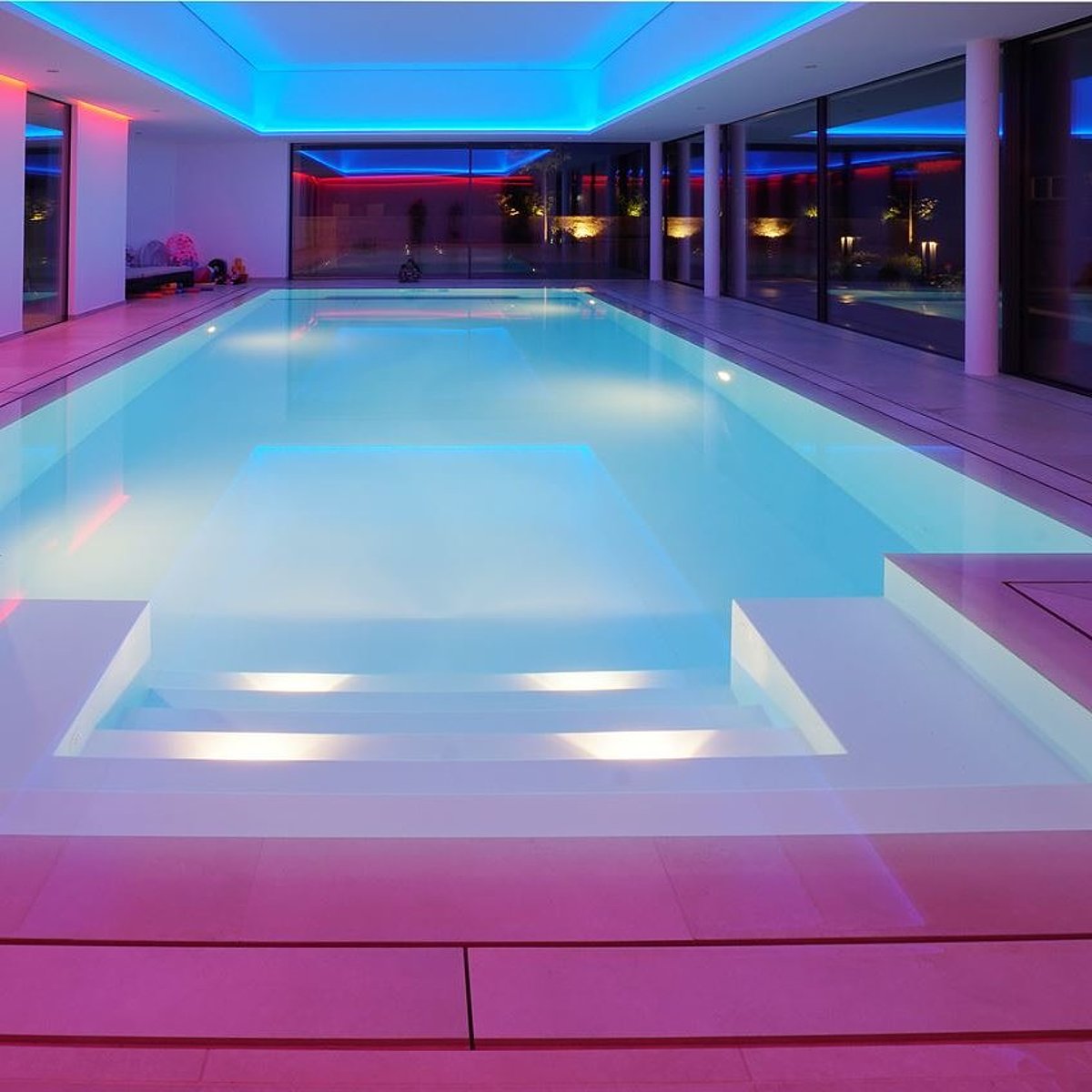 Binnenzwembad met paarsblauwe verlichting.