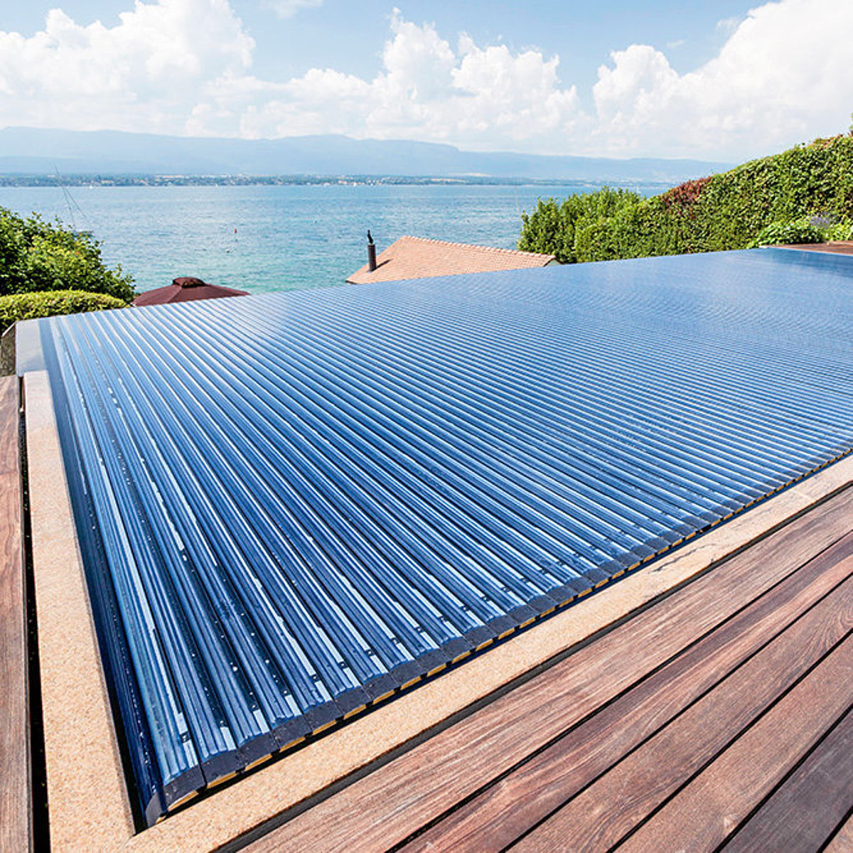 Ein in die Terrasse integriertes Schwimmbecken mit geschlossener Solar-Rollladenabdeckung.