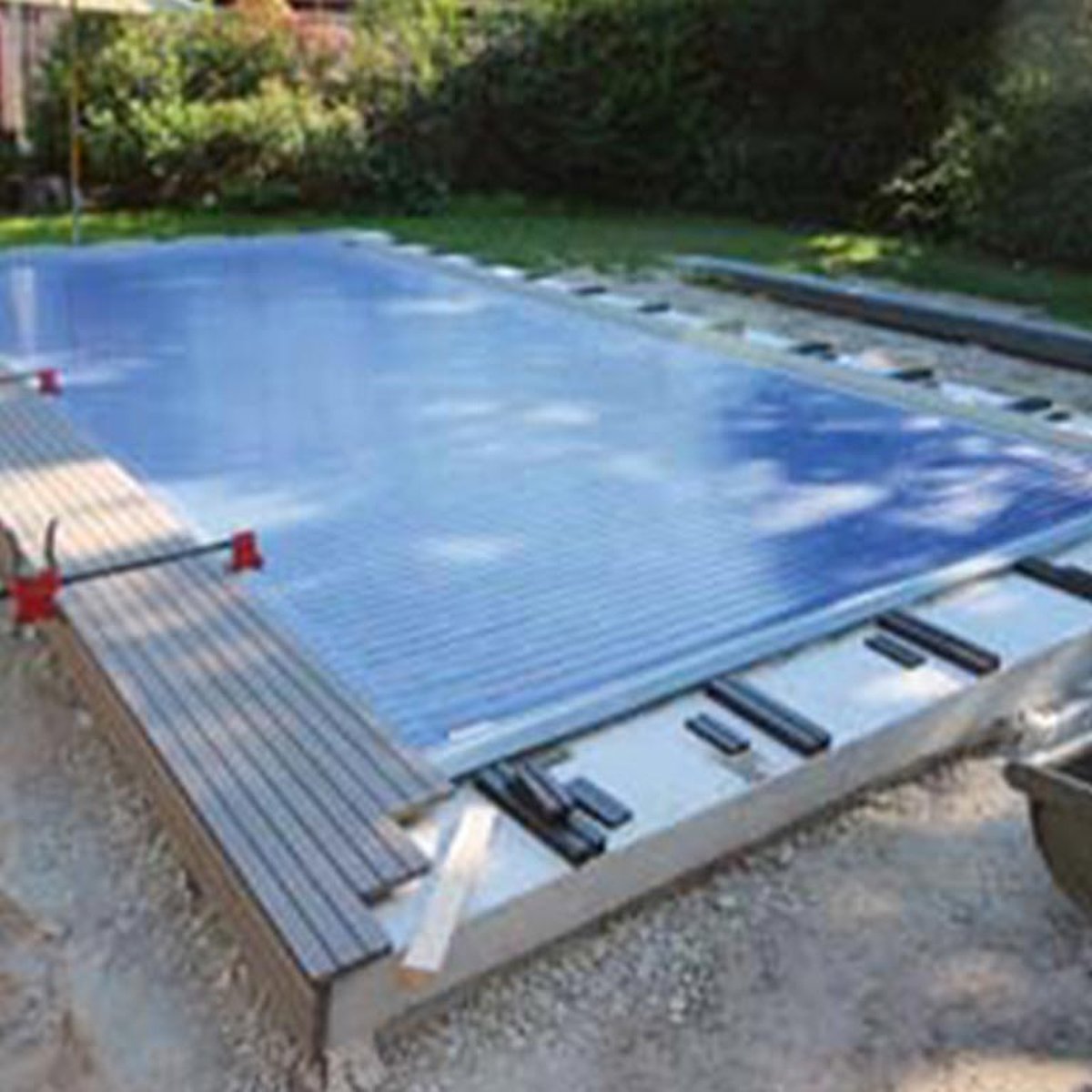 Zwembad met zonne-rolluik en houten dek als zwembadrand.
