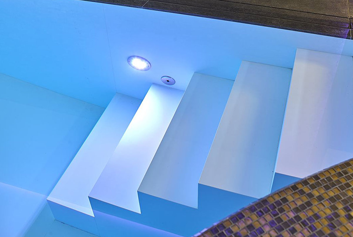 Ein LED-Strahler im Treppenbereich eines Pools. 