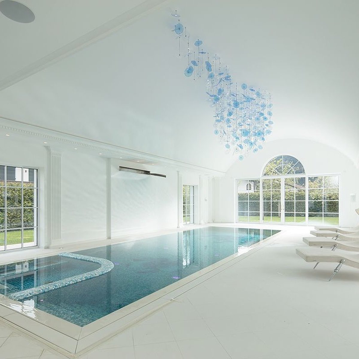 Zicht op een binnenruimte met gewelfd plafond en een zwembad met turkooiskleurige mozaïeksteentjes.