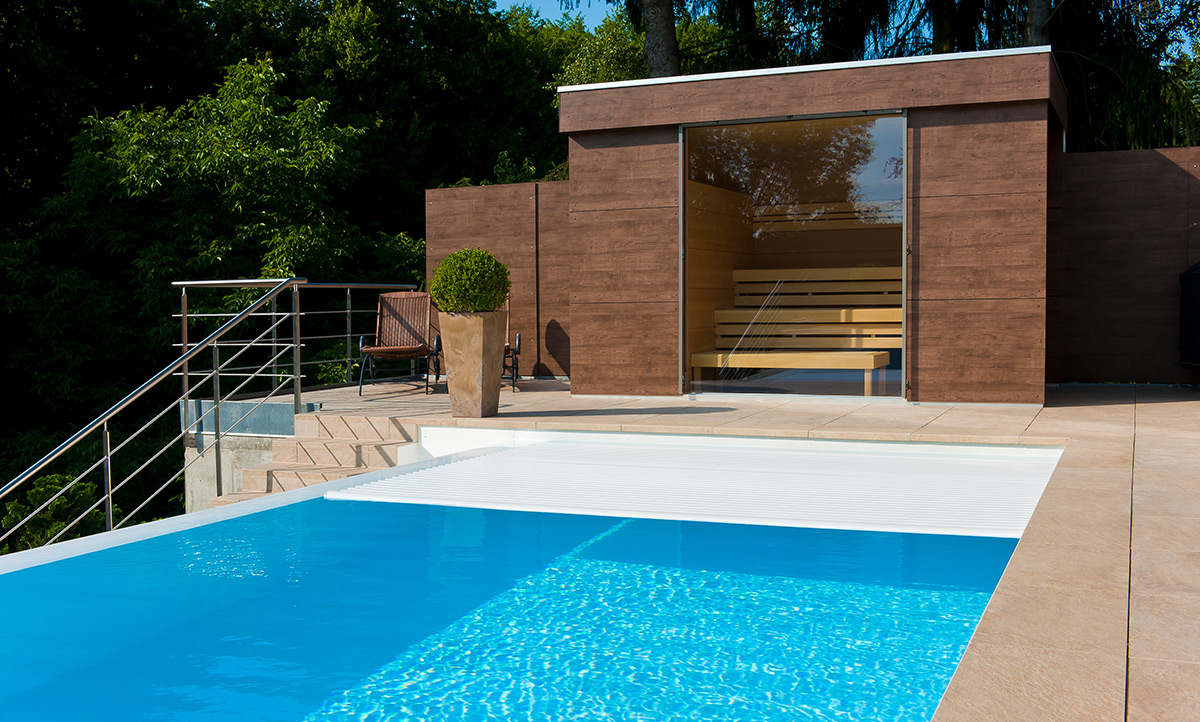 Eine Außensauna in direkter Nähe zu einem Pool mit Poolabdeckung.