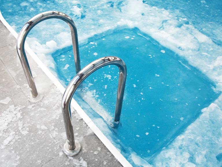 Ein Pool – die Schwimmfläche ist zugefroren. Im Bereich der Beckenleiter wurde eine rechteckige Fläche vom Eis befreit.